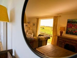 a mirror reflecting a living room with a couch and a window at Edenville in Girthon