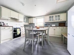 a kitchen with white cabinets and a table and chairs at Balloan Cottage-Uk7382 in Dornoch