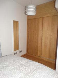 1 dormitorio con 1 cama y armario de madera en Málaga Apartamentos - Jinetes, 14, en Málaga