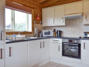 a kitchen with white cabinets and a stove top oven at Kingfisher Lodge- W43170 in Burn