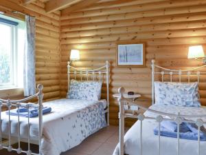 two beds in a log cabin bedroom with wooden walls at Kingfisher Lodge- W43170 in Burn +9 photos