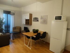 cocina y sala de estar con mesa y nevera en Málaga Apartamentos - Jinetes, 14, en Málaga