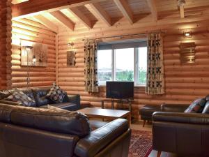a living room with leather furniture in a log cabin at Teal Lodge- Ukc2565 in Burn