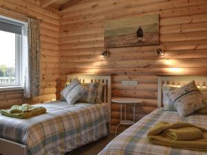 two beds in a log cabin bedroom with a table at Teal Lodge- Ukc2565 in Burn +2 photos