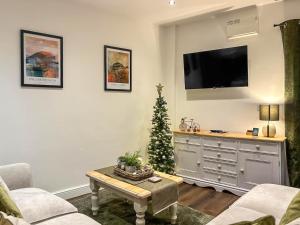 a living room with a christmas tree and a tv at Coachmans Cottage in Settle