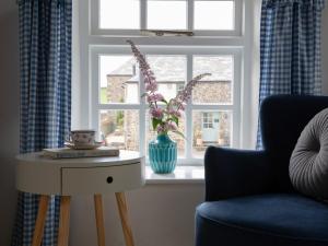 a room with a table with a vase of flowers in a window at The Coach House - Ukc4691 in Kilkhampton