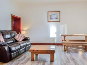 a living room with a leather couch and a table at Merrick Cottage - Uk7783 in Newton Stewart