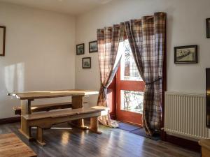 a table and a bench in a room with a window at Merrick Cottage - Uk7783 in Newton Stewart