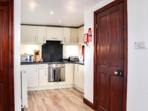 a kitchen with white cabinets and a wooden door at Merrick Cottage - Uk7783 in Newton Stewart