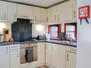 a kitchen with white cabinets and stainless steel appliances at Merrick Cottage - Uk7783 in Newton Stewart