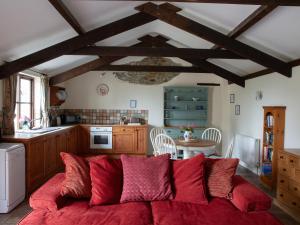 a living room with a red couch in a kitchen at Honeysuckle Cottage - Ukc4692 in Kilkhampton