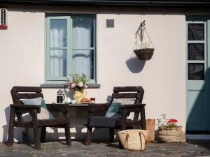 a patio table with two chairs and a basket on the wall at Honeysuckle Cottage - Ukc4692 in Kilkhampton
