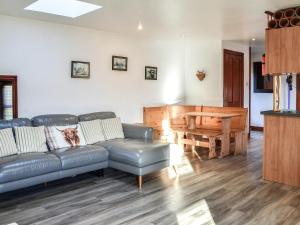 a living room with a leather couch and a piano at Maberry Cottage - Uk7784 in Newton Stewart