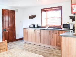 a kitchen with wooden cabinets and a sink and a window at Maberry Cottage - Uk7784 in Newton Stewart +5 photos