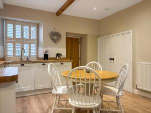 a kitchen with a wooden table and white chairs at Bailey Cottage in Skipton