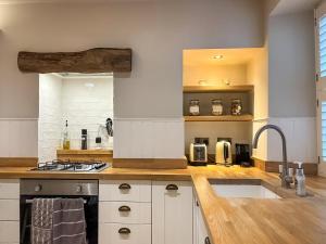a kitchen with white cabinets and a stove top oven at Bailey Cottage in Skipton +14 photos