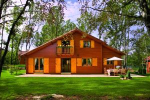 a large wooden house with a balcony on a yard at Résidence Souillac Golf & Country Club in Lachapelle-Auzac