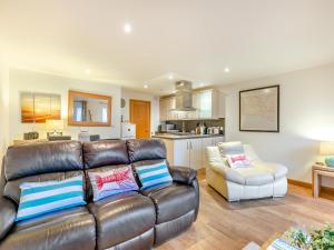 a living room with a leather couch and a kitchen at 20 Mount Brioni in Downderry