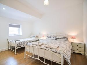 two beds in a bedroom with white walls and wood floors at Cottage 8 - Ukc3185 in York