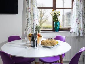 a white table with a plate of bread and a bottle of wine at Lavender Cottage - Ukc4695 in Kilkhampton