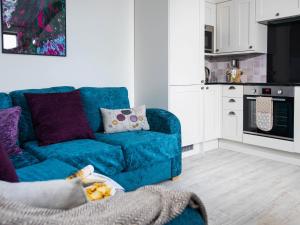 a living room with a blue couch and a kitchen at Lavender Cottage - Ukc4695 in Kilkhampton