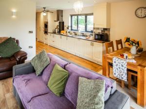 a living room with a purple couch and a kitchen at Caban Dulas - Ukc8195 in Dolau