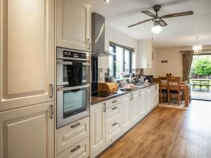 a kitchen with white cabinets and stainless steel appliances at Caban Dulas - Ukc8195 in Dolau
