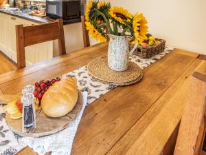 a table with a vase with a loaf of bread and a basket of fruit at Caban Dulas - Ukc8195 in Dolau