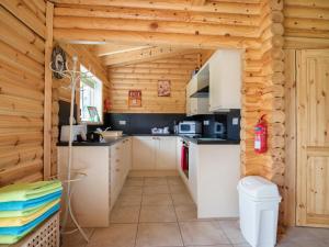 a kitchen in a cabin with wooden walls at Quail Lodge - W44304 in Burn
