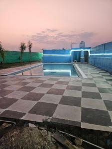 a swimming pool with a checkerboard floor and a building at Chillora cafe in Mahlān