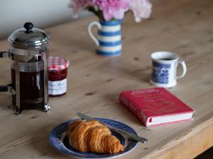 a table with a plate of croissant and a book at Rose Cottage - Ukc4693 in Kilkhampton
