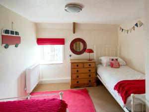 a bedroom with a twin bed and a red rug at Fuchia in Marhamchurch