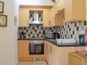 a kitchen with wooden cabinets and a sink at Stables Cottage-W42586 in Burn