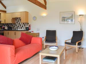 a living room with a red couch and a table at Stables Cottage-W42586 in Burn