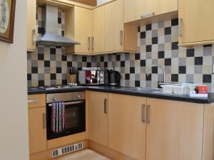 a kitchen with wooden cabinets and black and white tiles at Stables Cottage-W42586 in Burn