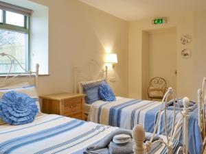 a bedroom with two beds with blue and white sheets at The Forge-W42942 in Burn