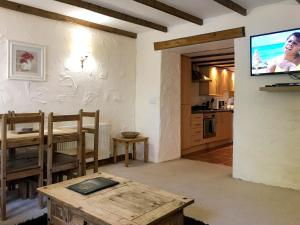 a living room with a table and a tv on a wall at Crantock Cottage- W40888 in Perranporth