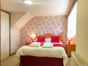 a bedroom with a large bed with red pillows at Crantock Cottage- W40888 in Perranporth +18 photos