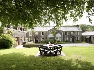 a park bench in front of a large house at Ty Cerbyd in Cilybebyll
