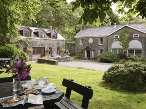 a picnic table in front of a large stone house at Ty Cerbyd in Cilybebyll