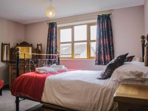 a bedroom with a bed and a window with curtains at Drovers Barn in Malpas