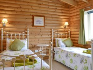 a log cabin bedroom with two beds and a table at Mallard Lodge - W43171 in Burn