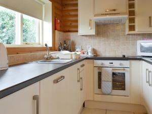 a kitchen with white cabinets and a sink at Mallard Lodge - W43171 in Burn