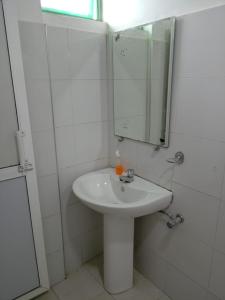 a white bathroom with a sink and a mirror at Bellamoon Resort in Trincomalee