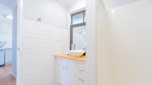 a white bathroom with a sink and a window at Nouveau Home in Epsom +11 photos