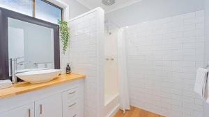 a white bathroom with a sink and a mirror at Nouveau Home in Epsom