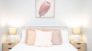 a bedroom with a white bed with two lamps at Nouveau Home in Epsom