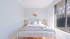 a white bedroom with a bed and a window at Nouveau Home in Epsom