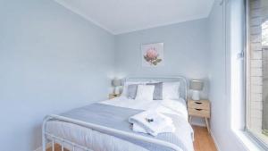 a bedroom with a white bed and a window at Nouveau Home in Epsom