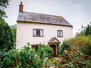 a white house with a garden in front of it at Farmhouse Wing in Malpas